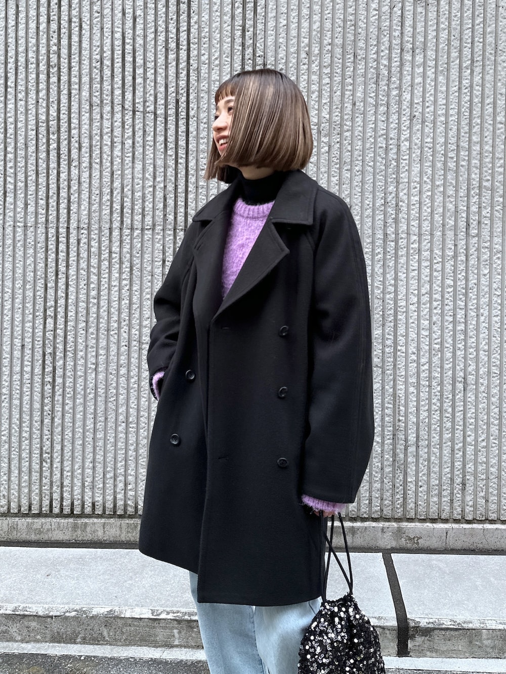 ブルー系のデニムパンツ、ブラック系のステンカラーコートを着用したレディースの冬コーディネートの5枚目の写真