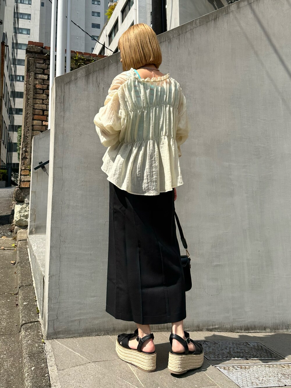 ブルー系のタンクトップ、ホワイト系のシャツ/ブラウス、ブラック系のスカートを着用したレディースの春コーディネートの2枚目の写真