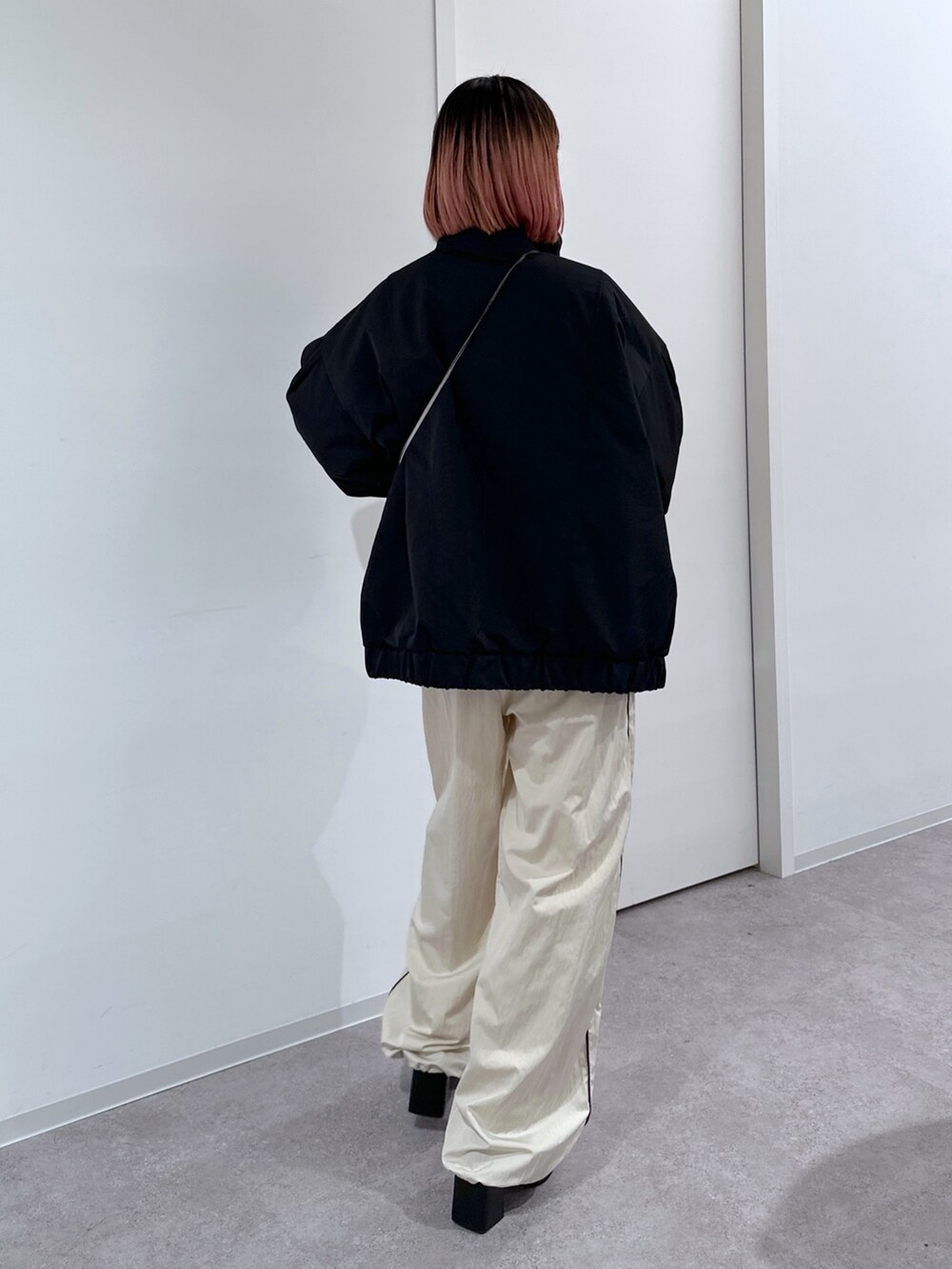 ブラック系のブルゾン、ホワイト系のスウェット、ホワイト系のその他パンツを着用したレディースの冬コーディネートの3枚目の写真