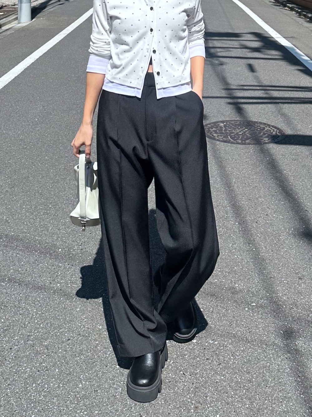 ホワイト系のTシャツ/カットソー、ブラック系のスラックス、ホワイト系のハンドバッグを着用したレディースの春コーディネートの6枚目の写真