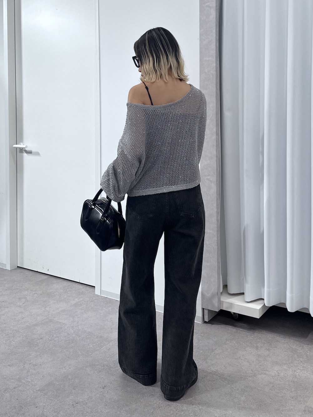 ブラック系のデニムパンツ、グレー系のニット/セーター、ブラック系のキャミソールを着用したレディースの春コーディネートの3枚目の写真