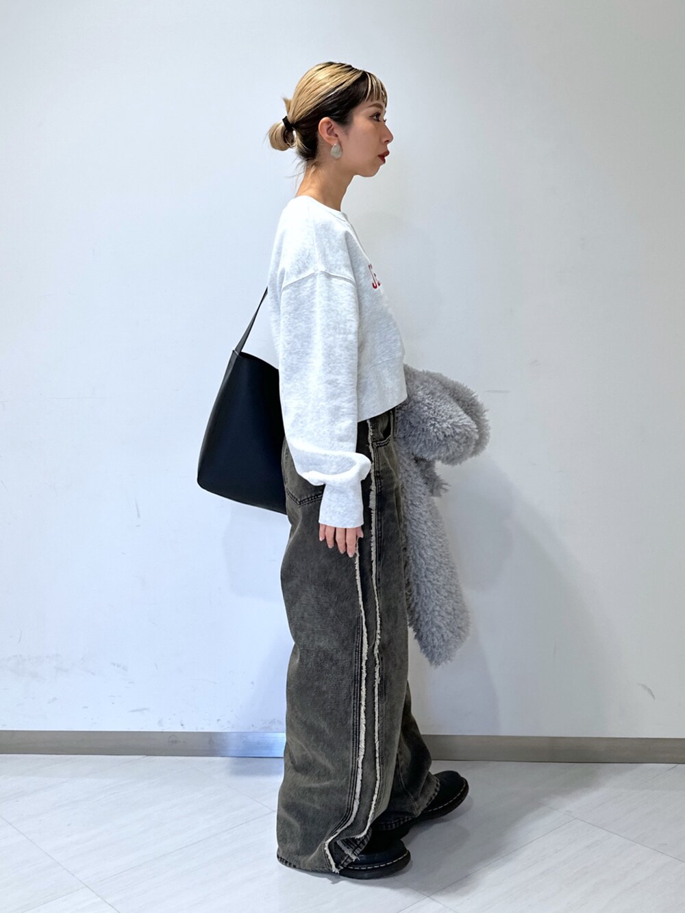 ホワイト系のスウェット、ブラック系のデニムパンツ、グレー系のブルゾンを着用したレディースの冬コーディネートの2枚目の写真