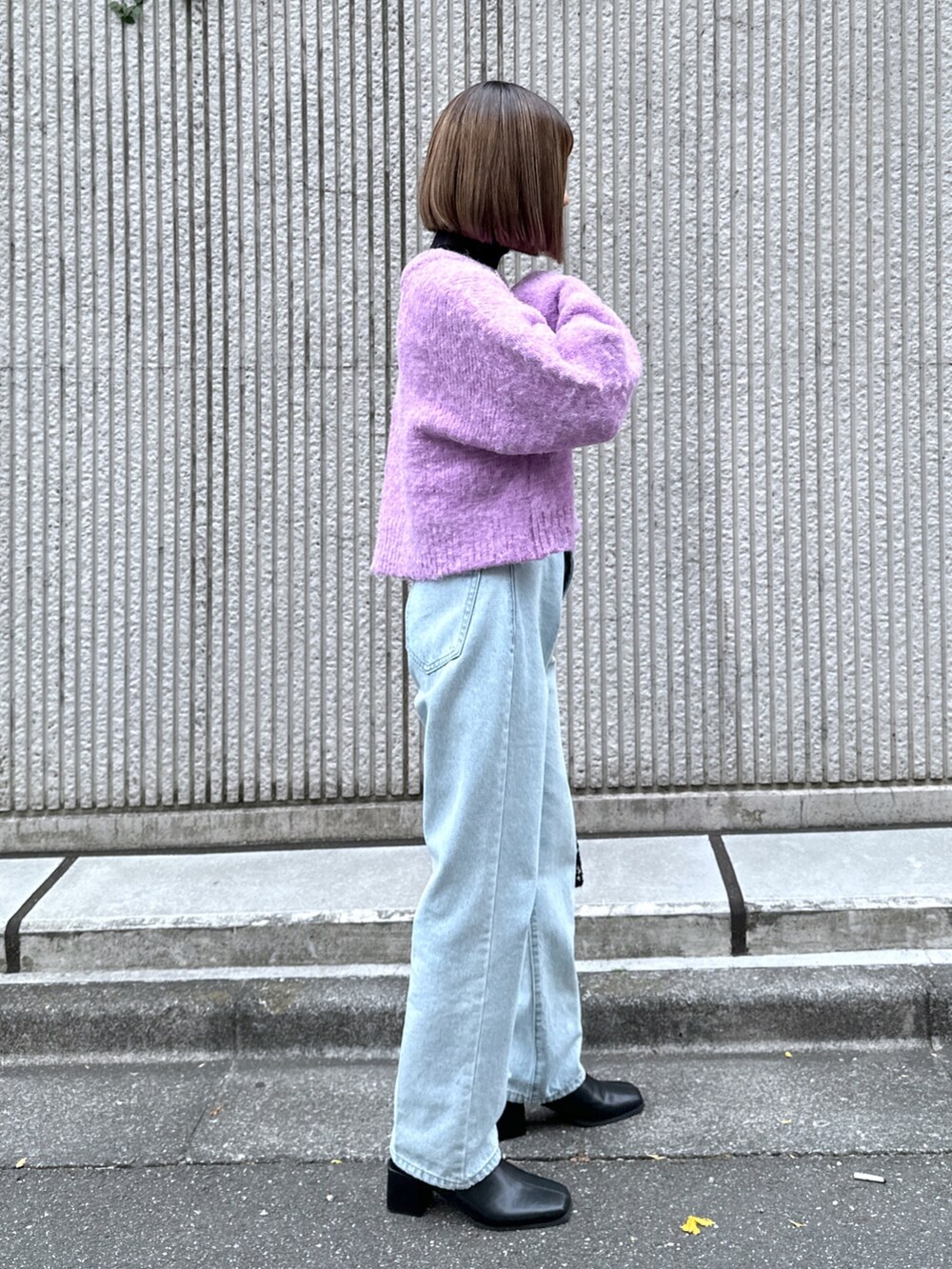 パープル系のニット/セーター、ブルー系のデニムパンツ、ブラック系のハンドバッグを着用したレディースの冬コーディネートの3枚目の写真
