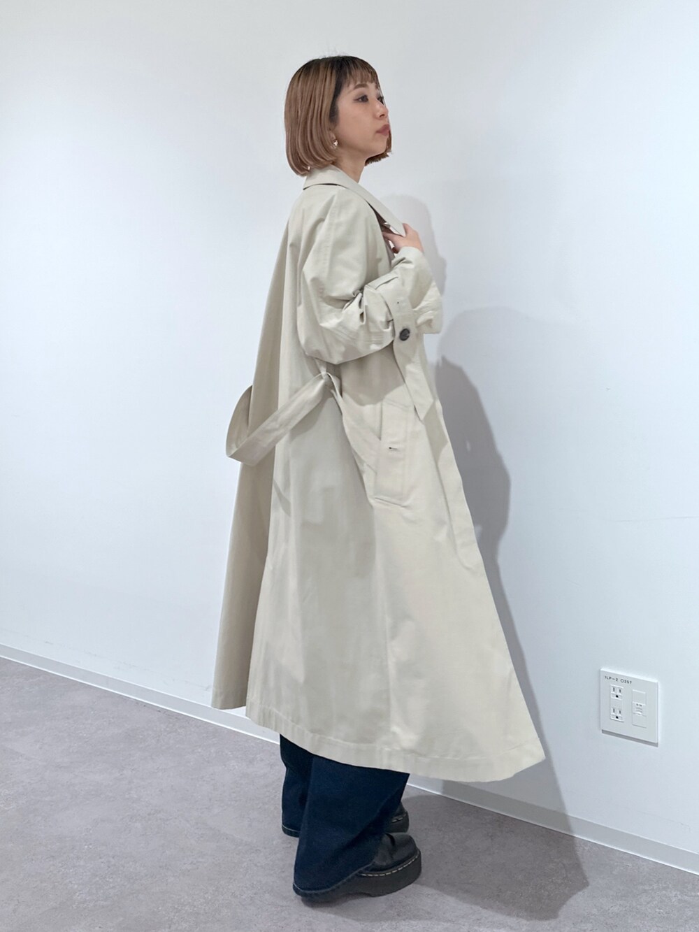 ベージュ系のトレンチコート、ブルー系のデニムパンツ、シルバー系のショルダーバッグを着用したレディースの春コーディネートの2枚目の写真