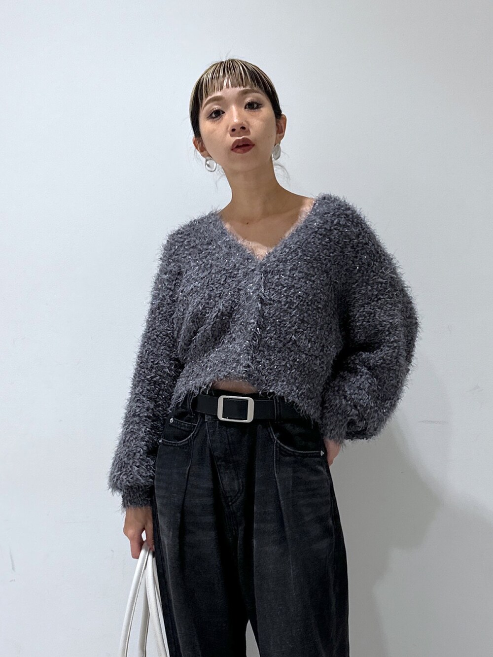 グレー系のカーディガン/ボレロ、ブラック系のデニムパンツ、ホワイト系のトートバッグを着用したレディースの秋コーディネートの4枚目の写真