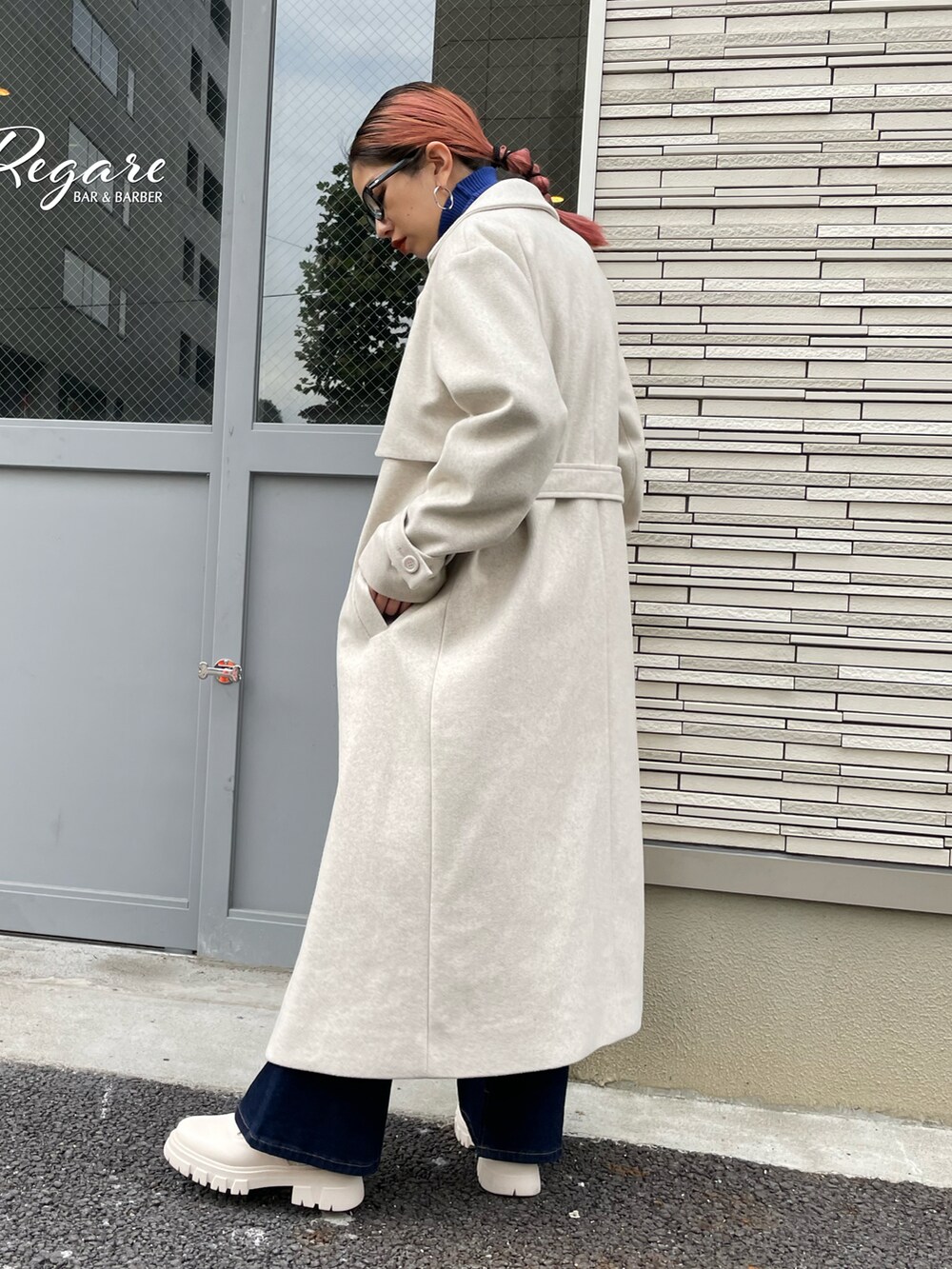 ベージュ系のチェスターコート、ブルー系のニット/セーター、ブルー系のデニムパンツを着用したレディースの秋コーディネートの2枚目の写真