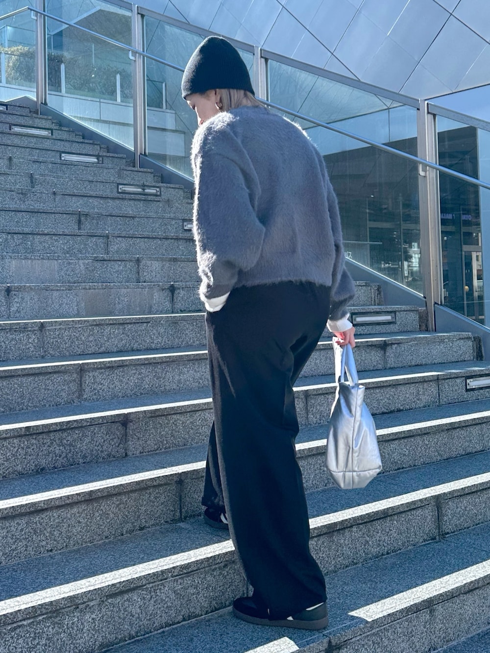 グレー系のカーディガン/ボレロ、ホワイト系のニット/セーター、ブラック系のスラックスを着用したレディースの冬コーディネートの2枚目の写真