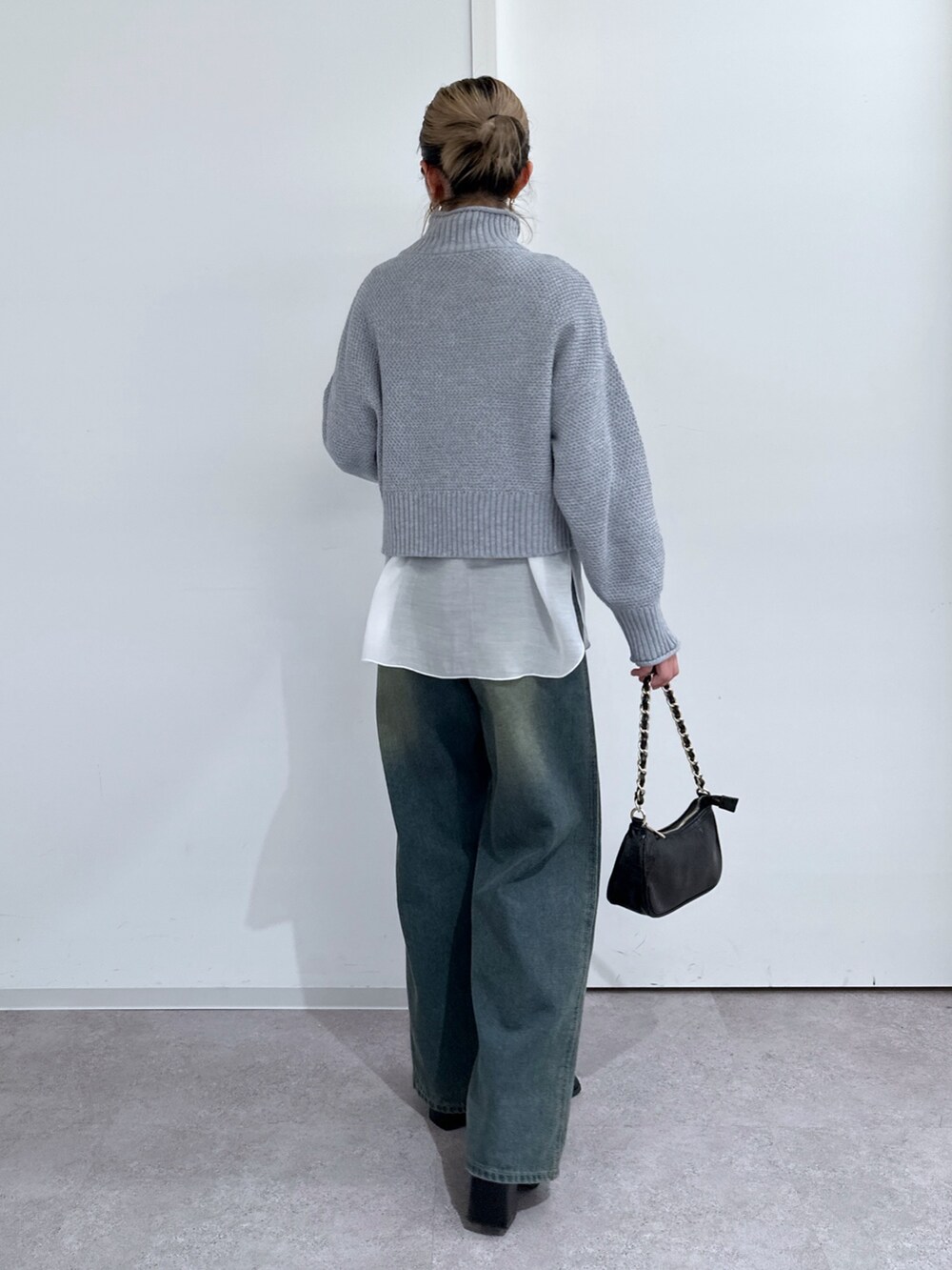 グレー系のニット/セーター、ホワイト系のTシャツ/カットソー、ブルー系のデニムパンツを着用したレディースの冬コーディネートの3枚目の写真