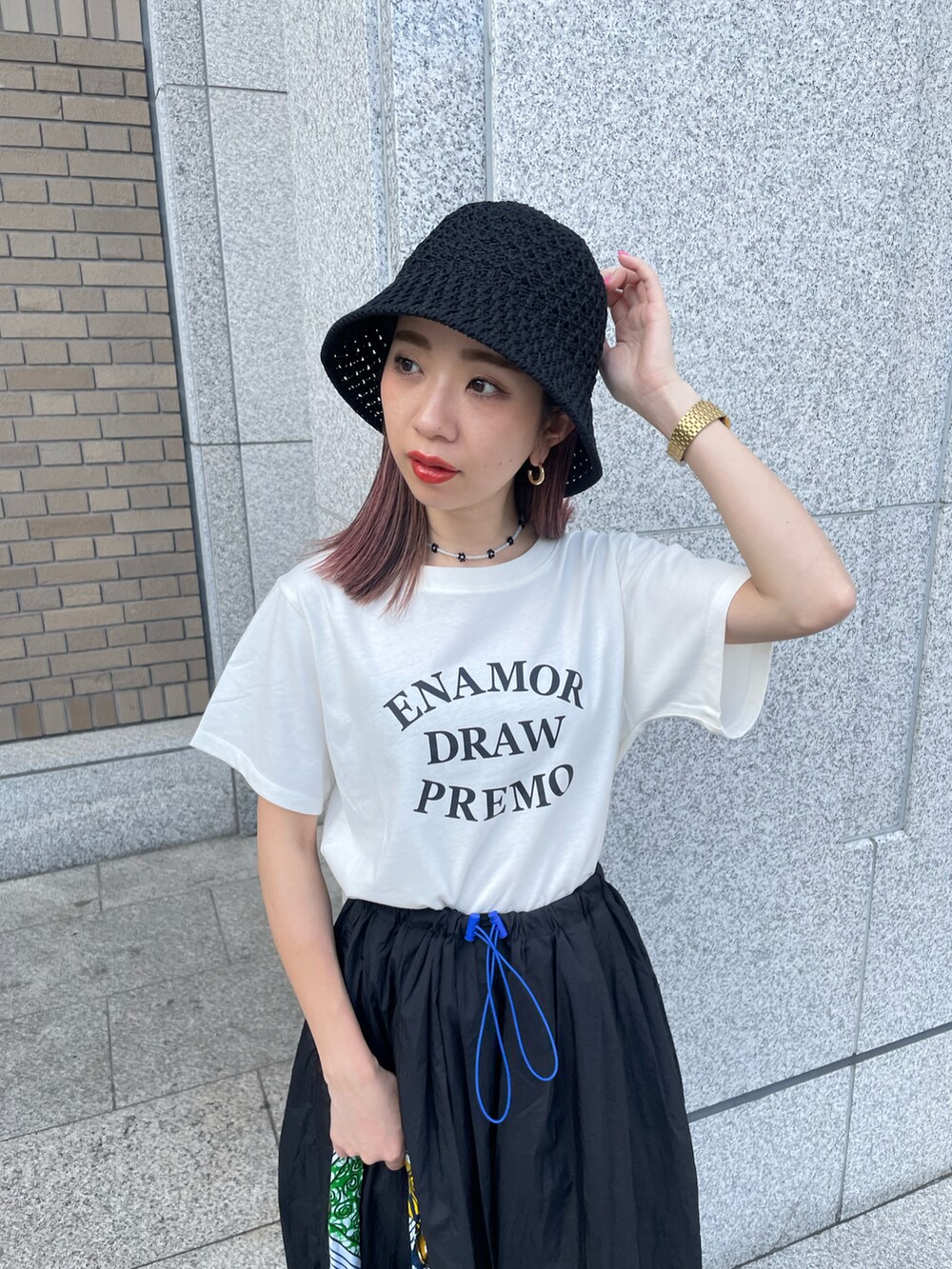 ブラック系のスカート、グリーン系のトートバッグ、ブラック系のサンダルを着用したレディースの夏コーディネートの2枚目の写真