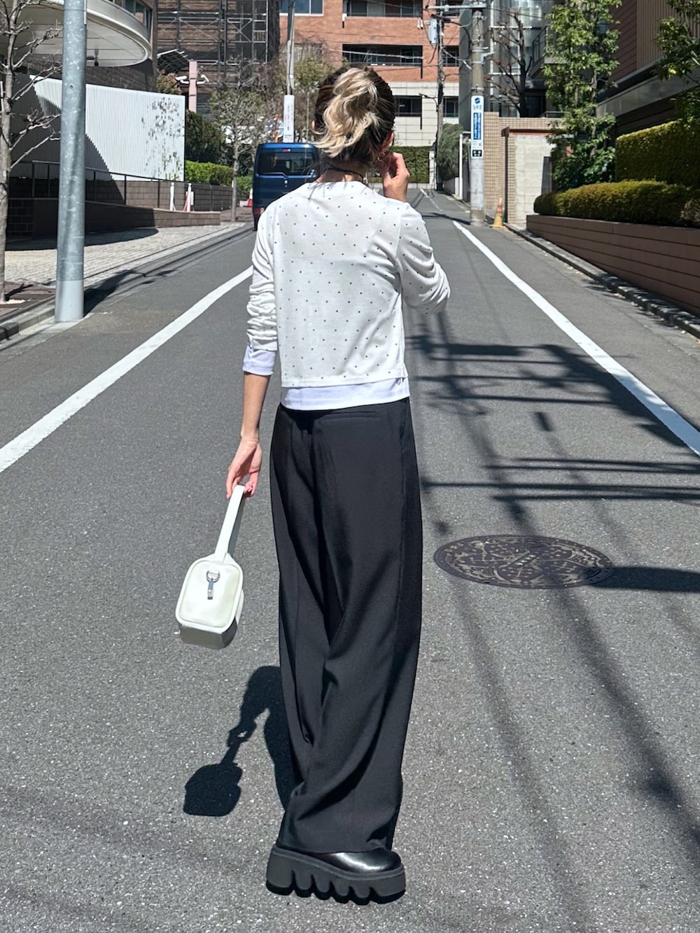 ホワイト系のTシャツ/カットソー、ブラック系のスラックス、ホワイト系のハンドバッグを着用したレディースの春コーディネートの3枚目の写真