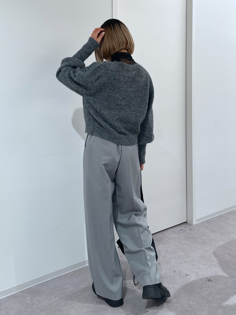 グレー系のスラックス、グレー系のニット/セーター、ブラック系のショルダーバッグを着用したレディースの冬コーディネートの3枚目の写真