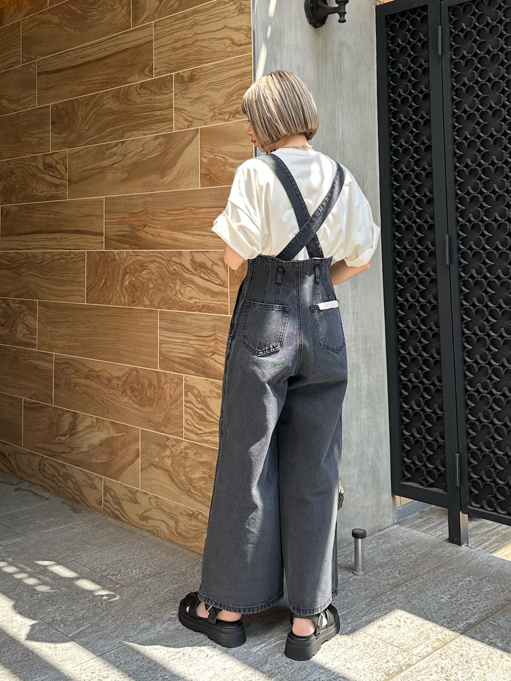 ブラック系のデニムパンツ、グリーン系のトートバッグ、ブラック系のサンダルを着用したレディースの春コーディネートの3枚目の写真