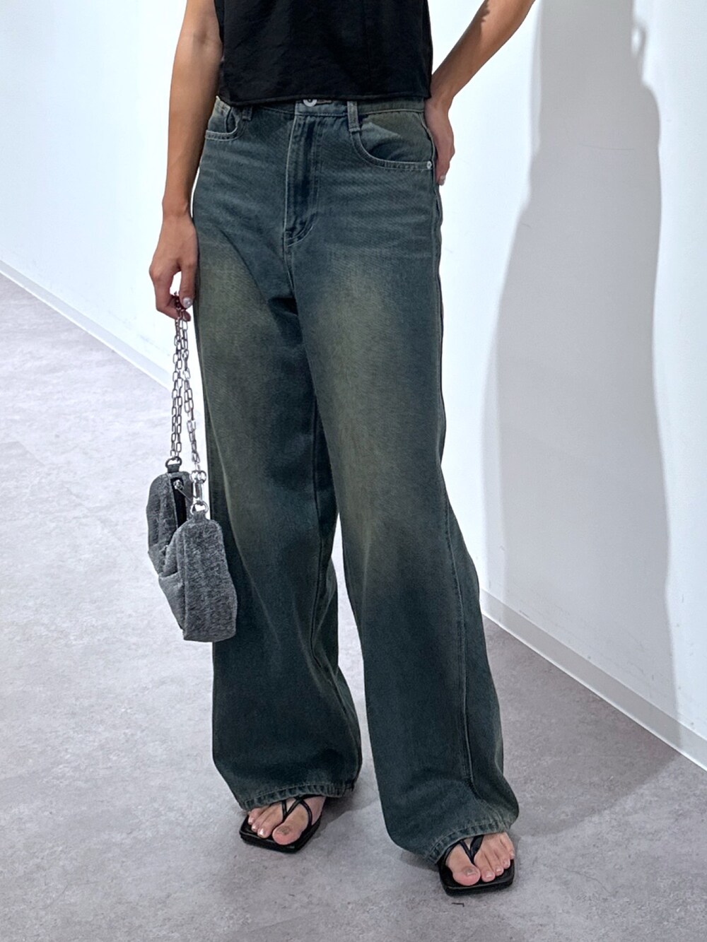 ブラック系のキャミソール、ブルー系のデニムパンツ、シルバー系のハンドバッグを着用したレディースの秋コーディネートの5枚目の写真