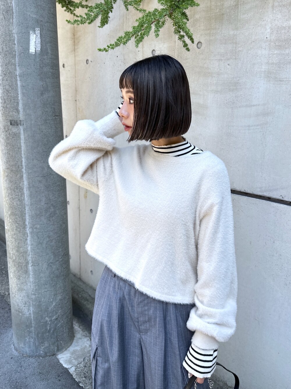 グレー系のスラックス、ブラック系のショルダーバッグ、ホワイト系のニット/セーターを着用したレディースの秋コーディネートの4枚目の写真
