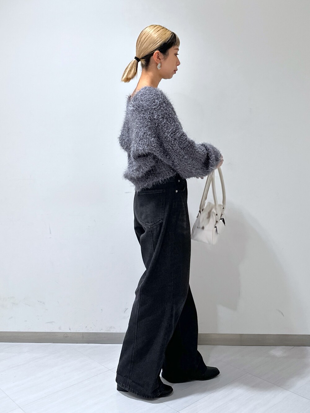グレー系のカーディガン/ボレロ、ブラック系のデニムパンツ、ホワイト系のトートバッグを着用したレディースの秋コーディネートの2枚目の写真