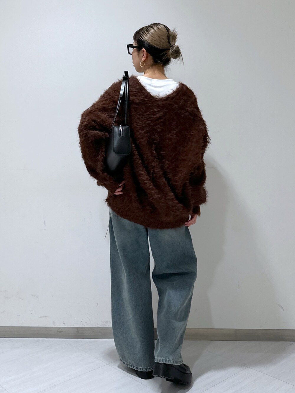 ブラウン系のカーディガン/ボレロ、ホワイト系のTシャツ/カットソー、ブルー系のデニムパンツを着用したレディースの冬コーディネートの3枚目の写真