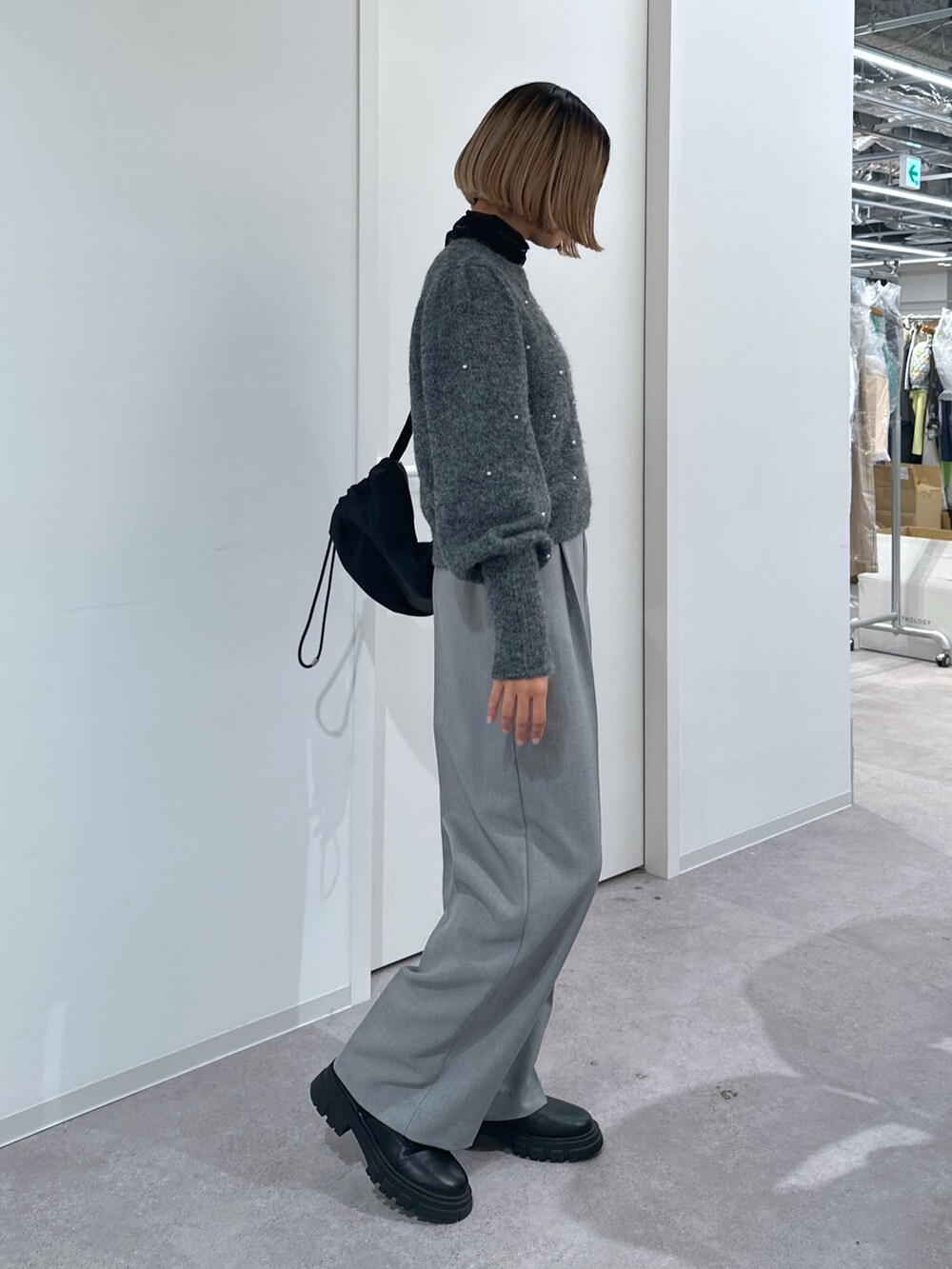 グレー系のスラックス、グレー系のニット/セーター、ブラック系のショルダーバッグを着用したレディースの冬コーディネートの2枚目の写真