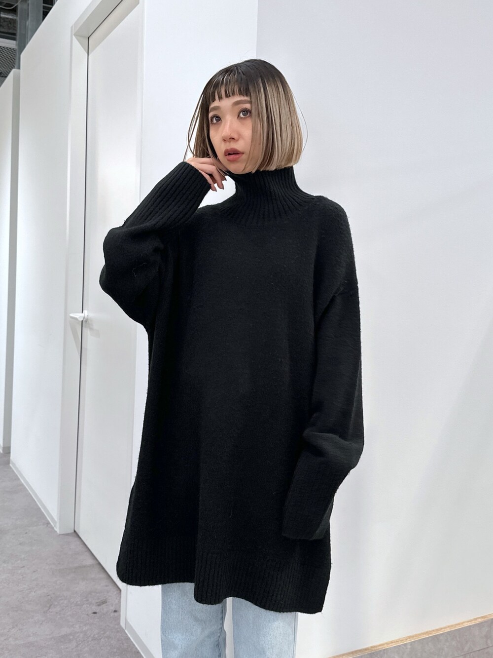 ブラック系のニット/セーター、ブラック系のハンドバッグ、ブルー系のデニムパンツを着用したレディースの冬コーディネートの4枚目の写真