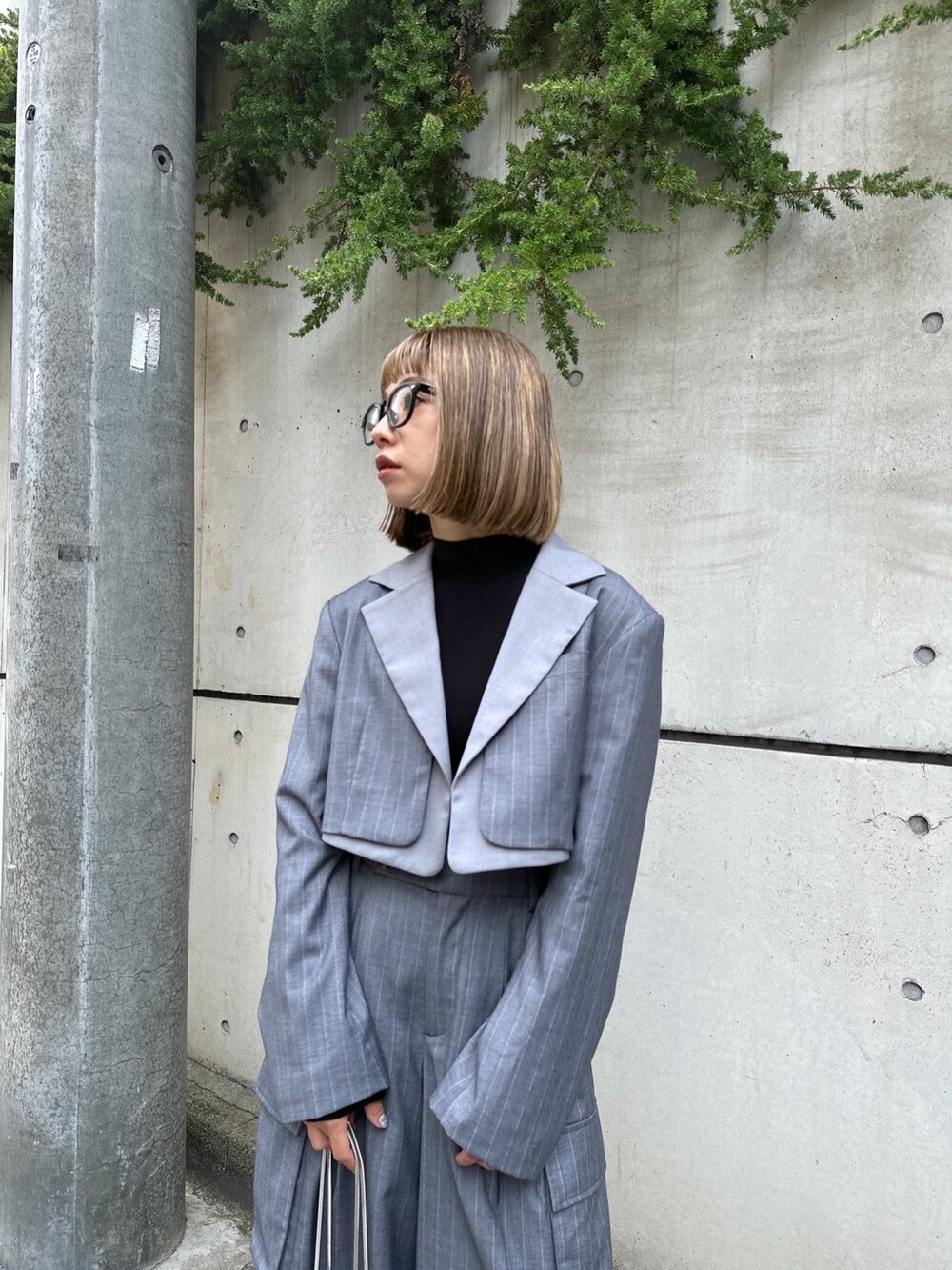 グレー系のスラックス、グレー系のテーラードジャケット、ブラック系のニット/セーターを着用したレディースの秋コーディネートの2枚目の写真