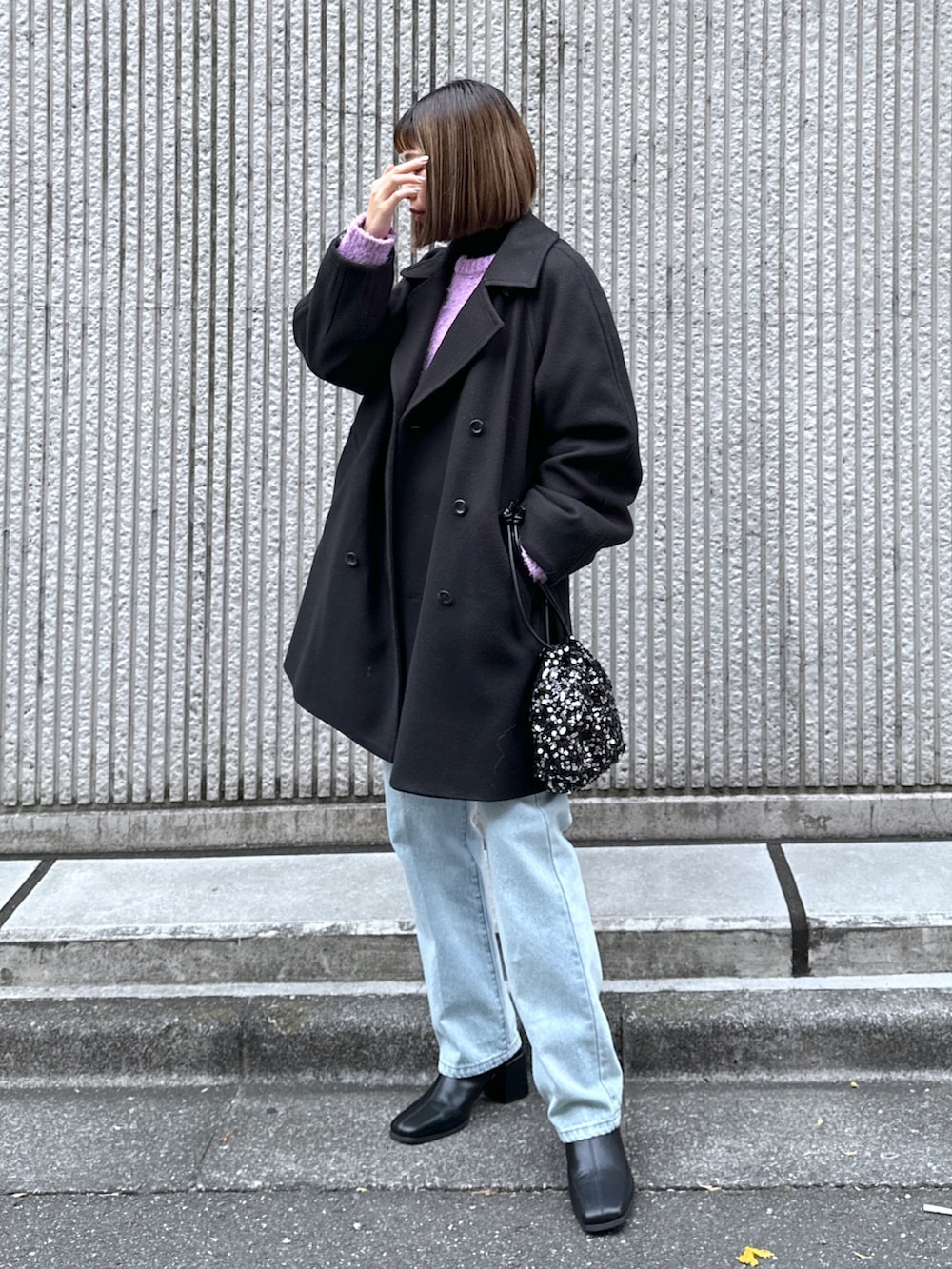 ブルー系のデニムパンツ、ブラック系のステンカラーコートを着用したレディースの冬コーディネートの2枚目の写真