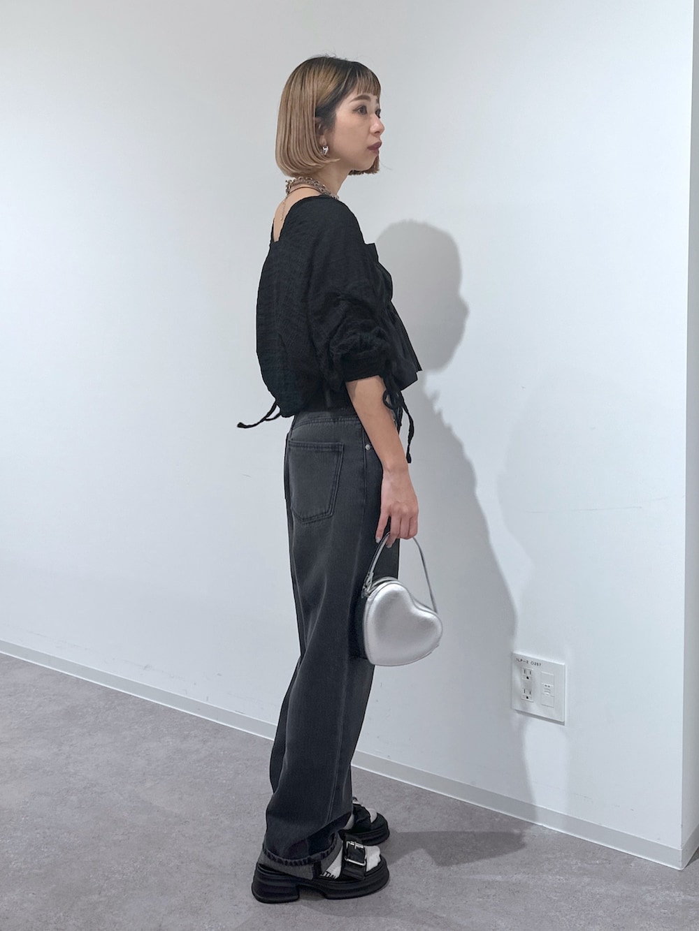 ブラック系のデニムパンツ、シルバー系のショルダーバッグ、ブラック系のサンダルを着用したレディースの春コーディネートの2枚目の写真