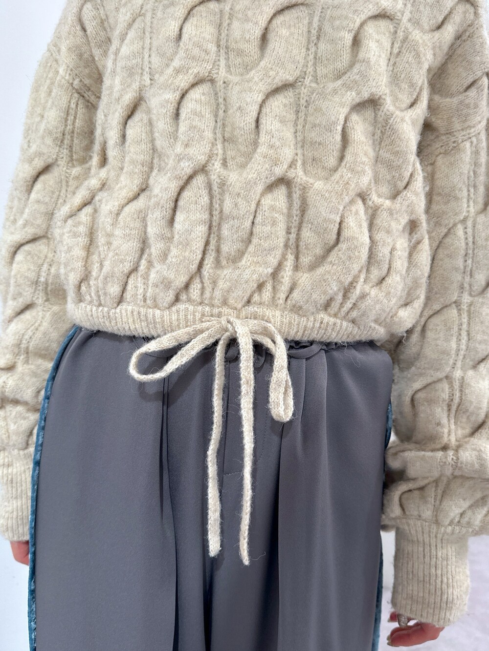 ホワイト系のニット/セーター、グレー系のその他パンツ、ブラック系のショルダーバッグを着用したレディースの冬コーディネートの5枚目の写真