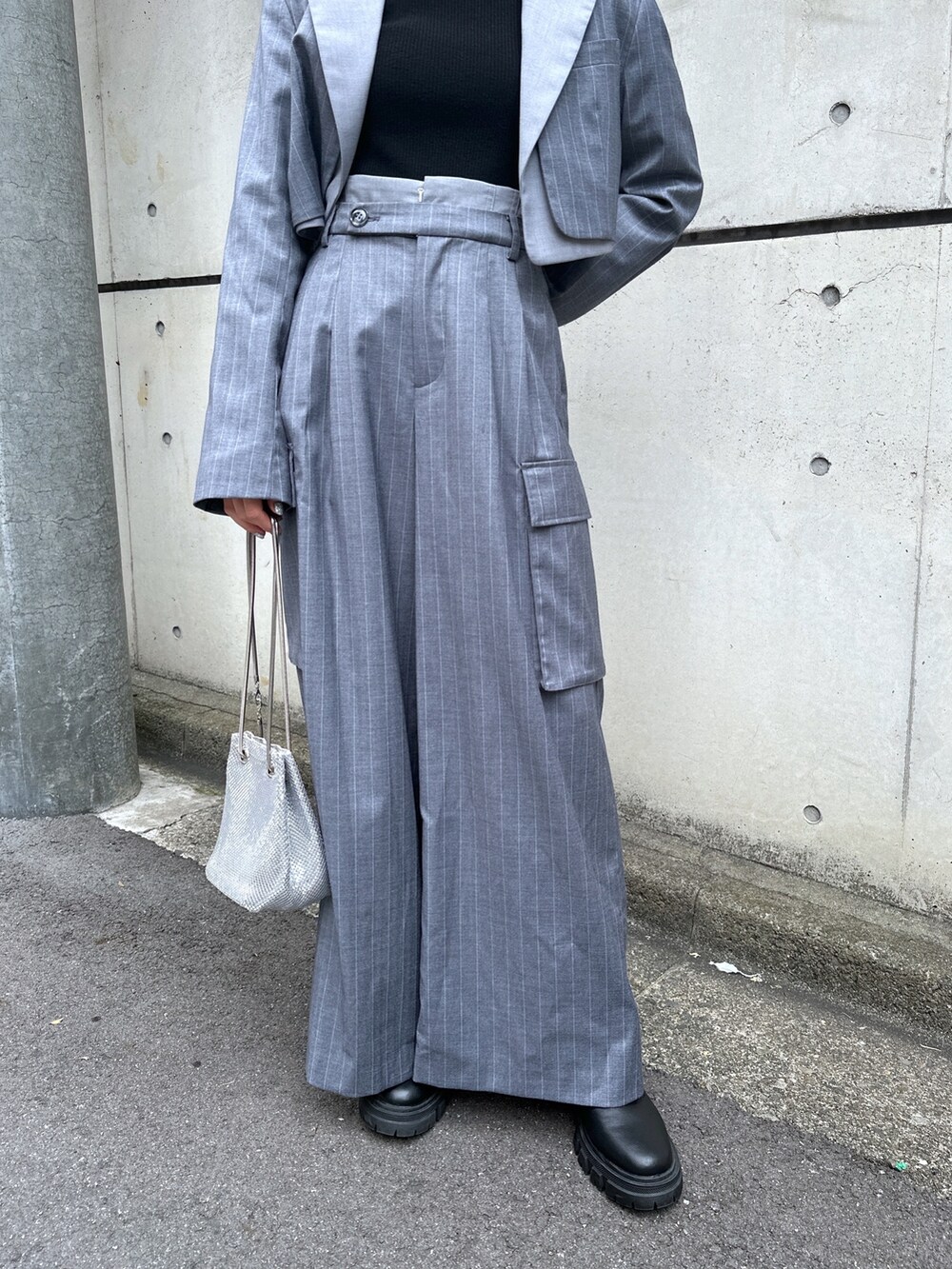 グレー系のスラックス、グレー系のテーラードジャケット、ブラック系のニット/セーターを着用したレディースの秋コーディネートの4枚目の写真