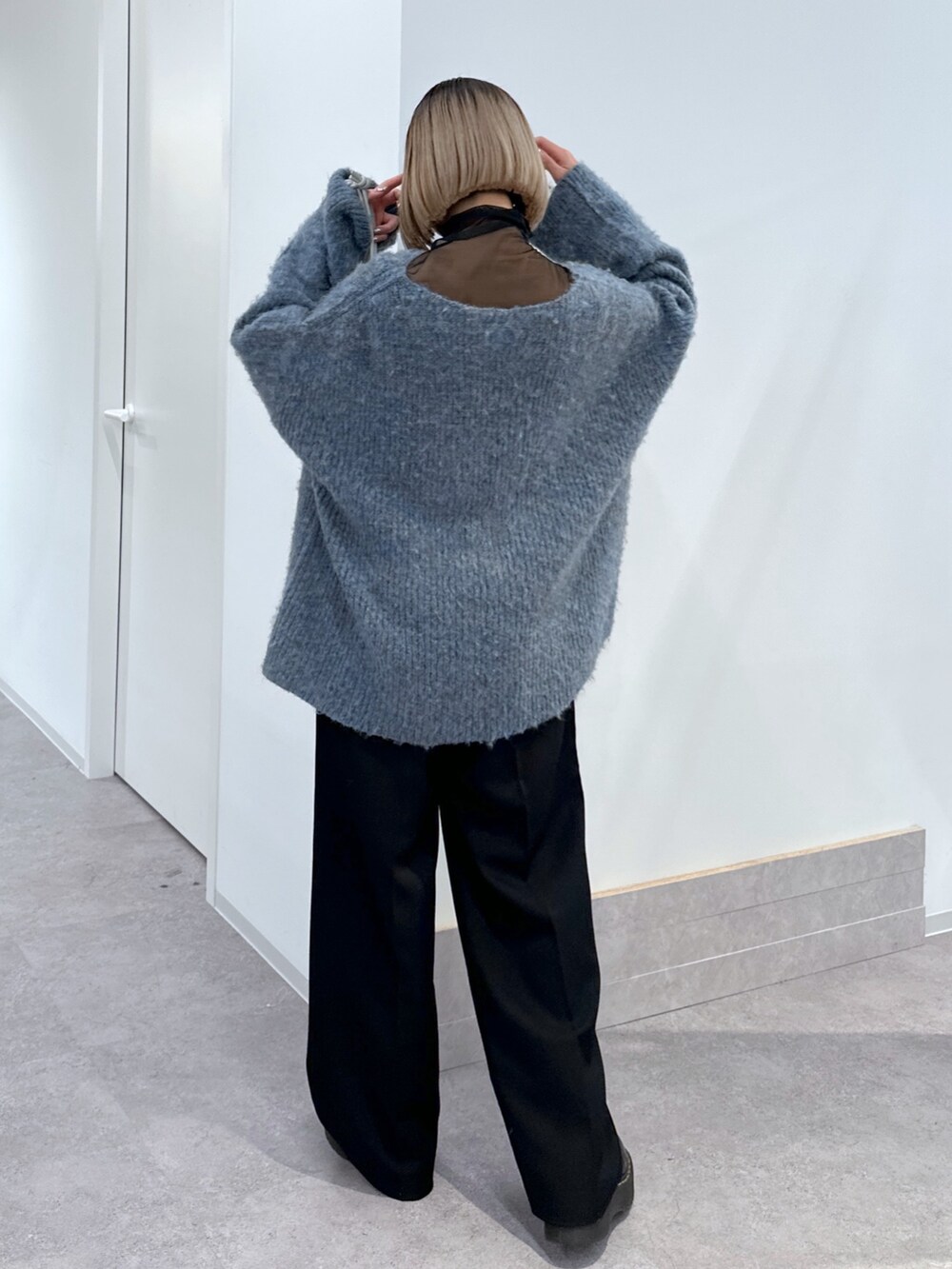 ブルー系のニット/セーター、ブラック系のTシャツ/カットソー、ブラック系のスラックスを着用したレディースの冬コーディネートの3枚目の写真