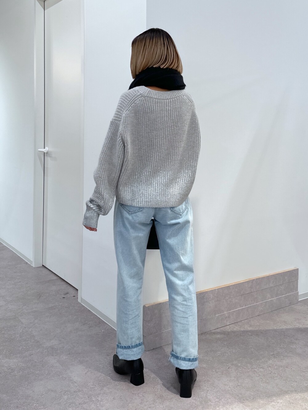 グレー系のニット/セーター、ブルー系のデニムパンツ、ブラック系のショルダーバッグを着用したレディースの冬コーディネートの3枚目の写真