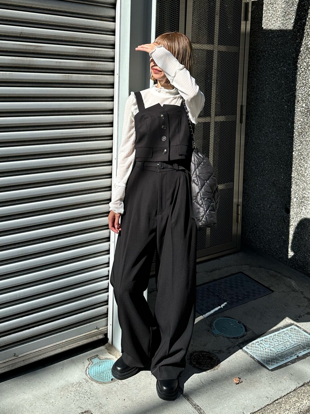 ブラック系のトートバッグ、ホワイト系のTシャツ/カットソー、ブラック系のベストを着用したレディースの秋コーディネートの5枚目の写真