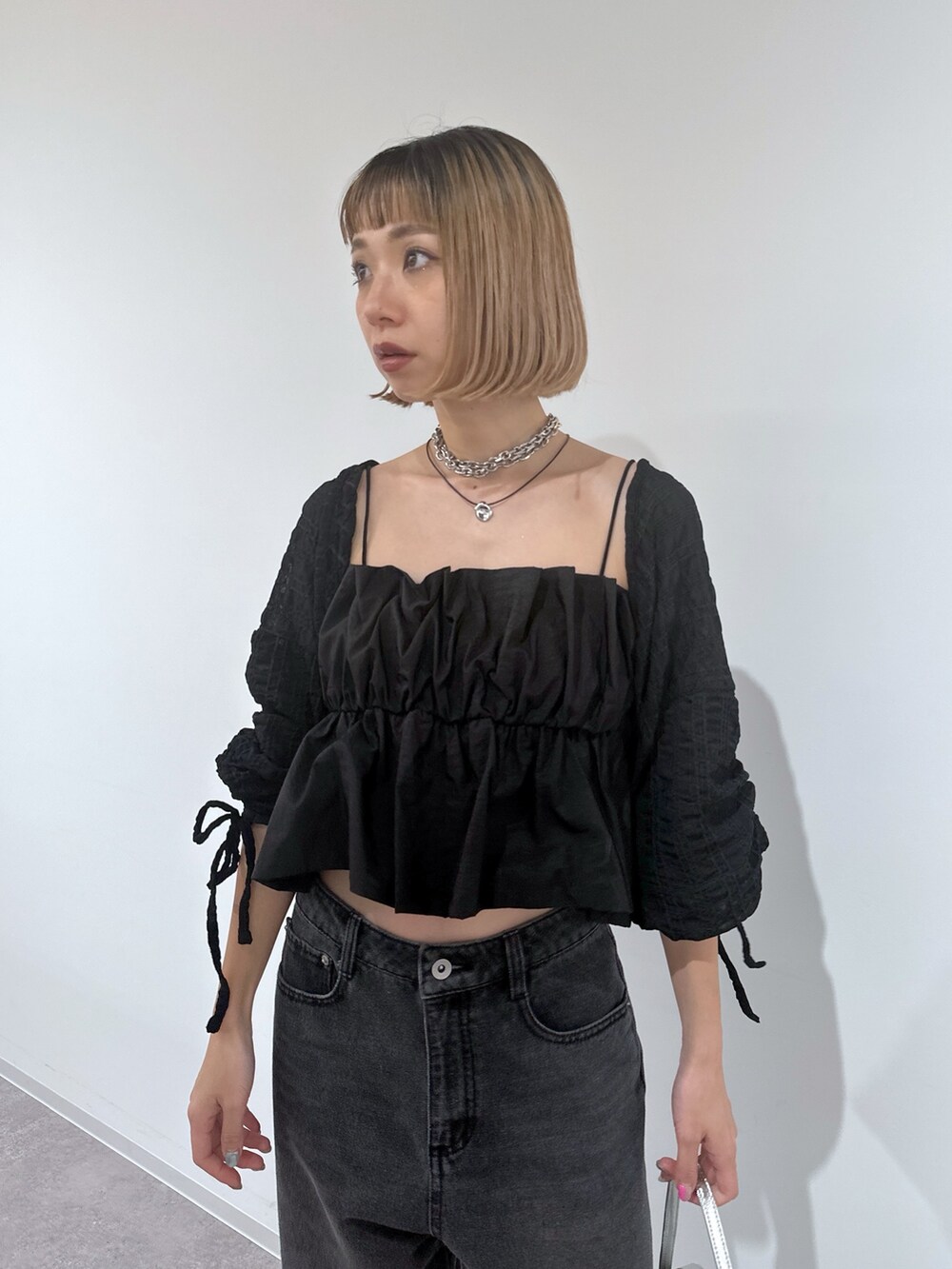 ブラック系のデニムパンツ、シルバー系のショルダーバッグ、ブラック系のサンダルを着用したレディースの春コーディネートの4枚目の写真