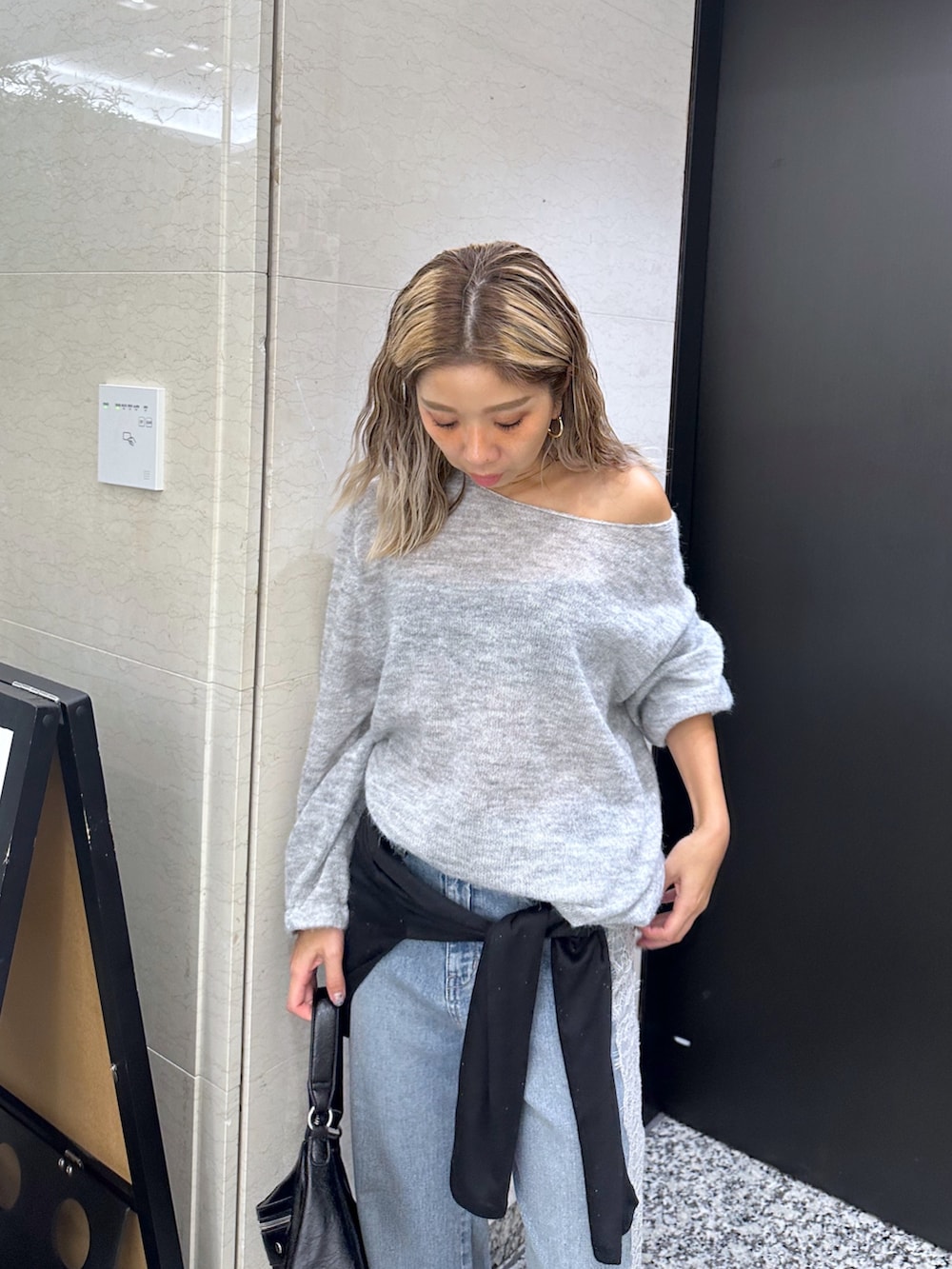 グレー系のニット/セーター、ブラック系のショルダーバッグ、ブラック系のTシャツ/カットソーを着用したレディースの秋コーディネートの4枚目の写真