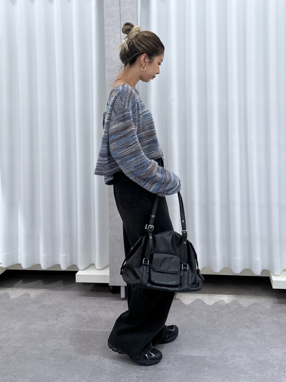 ブルー系のニット/セーター、ブラック系のデニムパンツ、ブラック系のショルダーバッグを着用したレディースの夏コーディネートの6枚目の写真