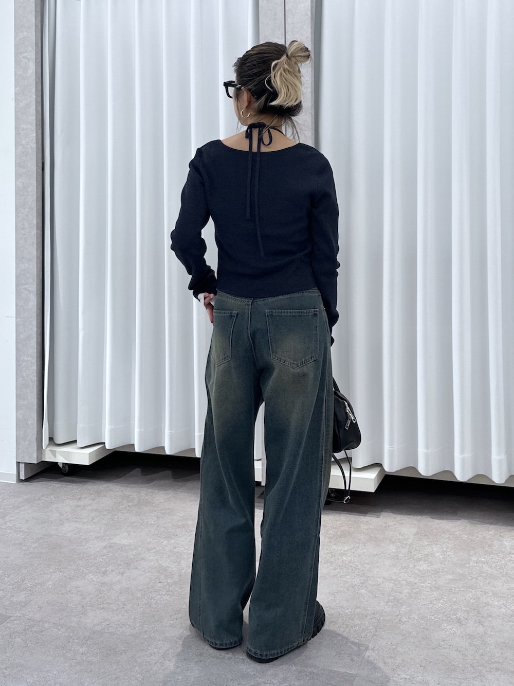 ブルー系のニット/セーター、ブルー系のデニムパンツ、ブラック系のハンドバッグを着用したレディースの春コーディネートの3枚目の写真