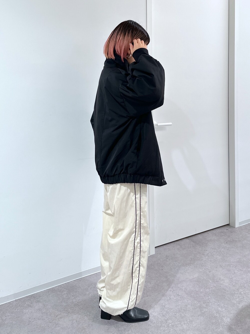 ブラック系のブルゾン、ホワイト系のスウェット、ホワイト系のその他パンツを着用したレディースの冬コーディネートの2枚目の写真