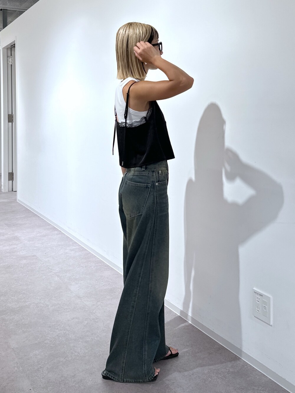 ブラック系のキャミソール、ブルー系のデニムパンツ、シルバー系のハンドバッグを着用したレディースの秋コーディネートの2枚目の写真