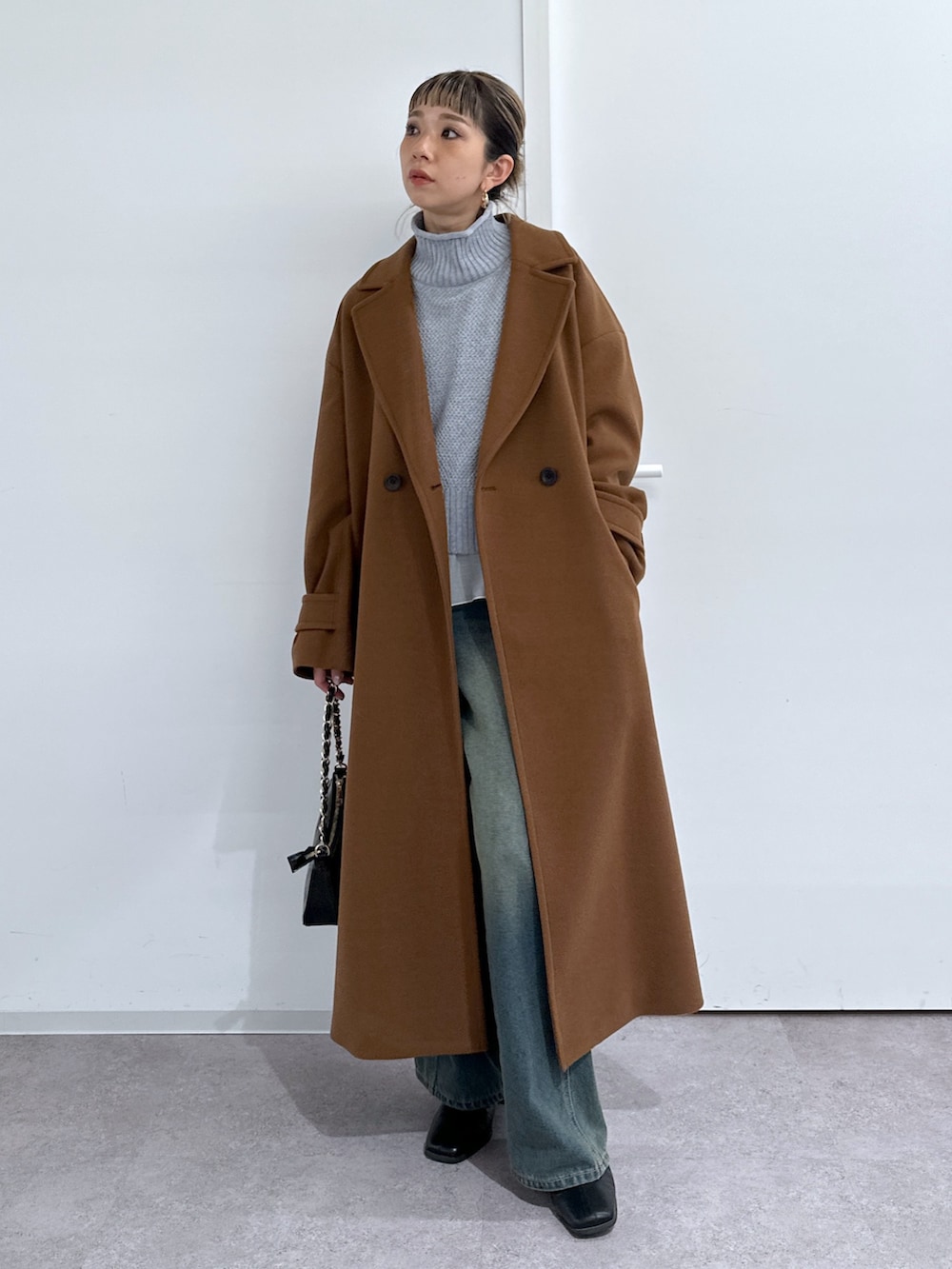 ブラウン系のチェスターコート、ホワイト系のTシャツ/カットソー、グレー系のニット/セーターを着用したレディースの冬コーディネートの4枚目の写真