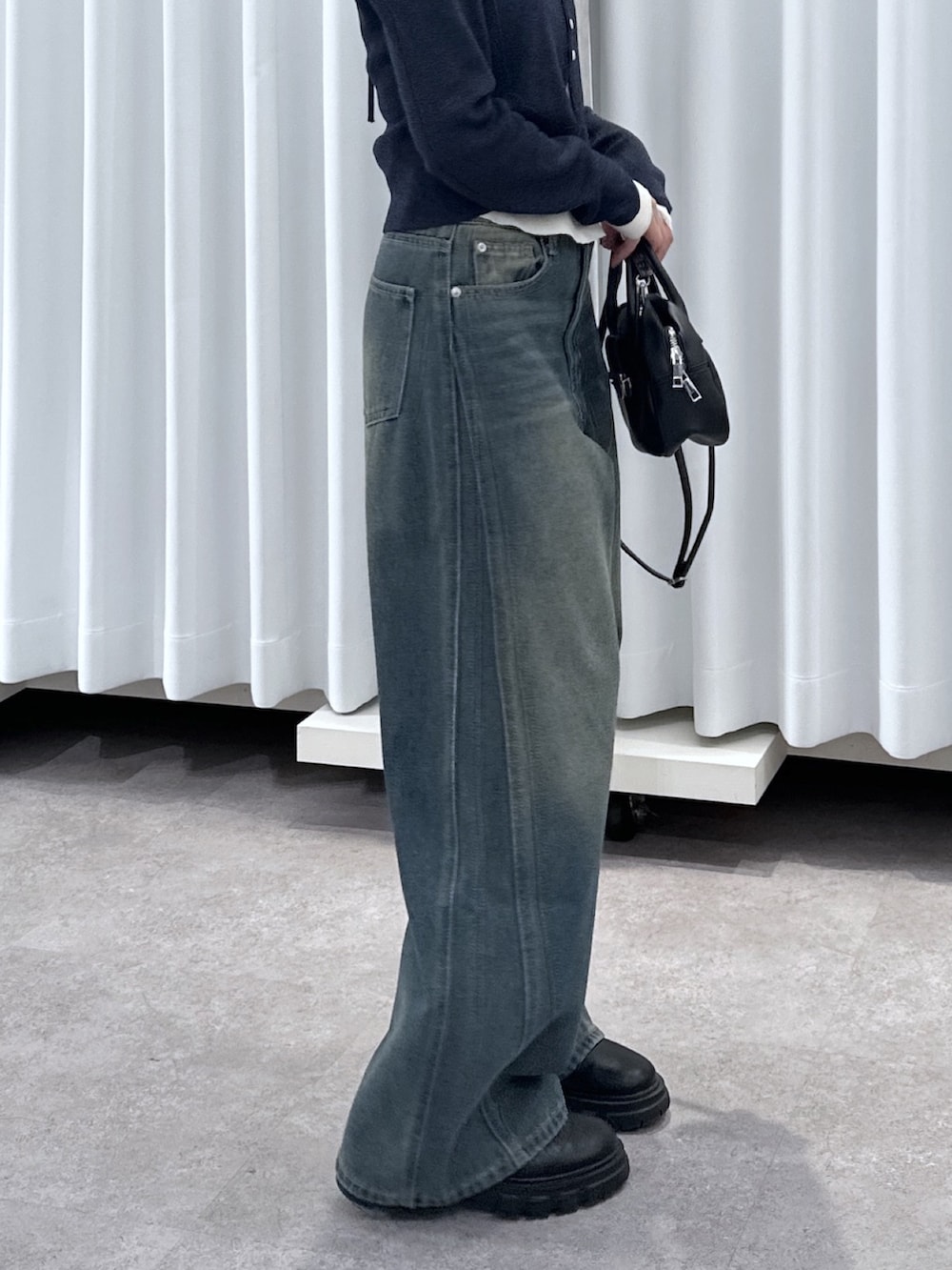 ブルー系のニット/セーター、ブルー系のデニムパンツ、ブラック系のハンドバッグを着用したレディースの春コーディネートの7枚目の写真