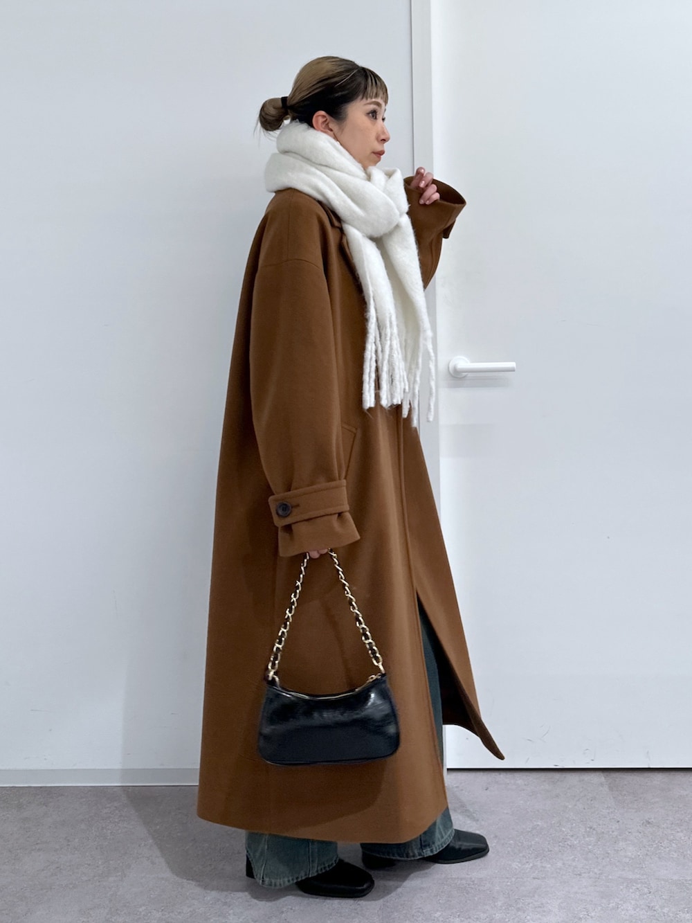 ブラウン系のチェスターコート、ホワイト系のTシャツ/カットソー、グレー系のニット/セーターを着用したレディースの冬コーディネートの2枚目の写真