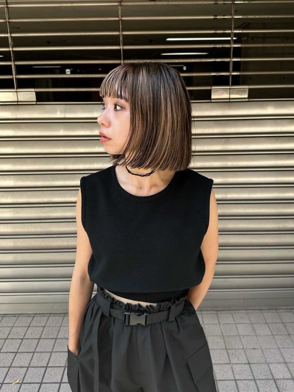 ブラック系のベスト、ブラック系のカーゴパンツ、ホワイト系のサンダルを着用したレディースの夏コーディネートの2枚目の写真