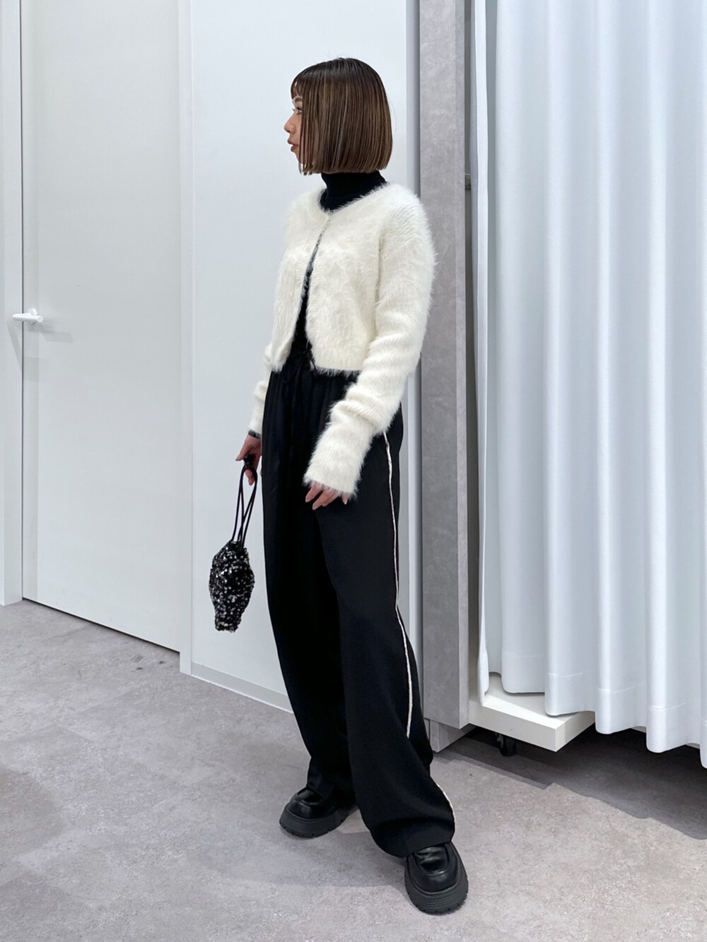 ブラック系のその他パンツ、ブラック系のハンドバッグ、ホワイト系のカーディガン/ボレロを着用したレディースの冬コーディネートの4枚目の写真