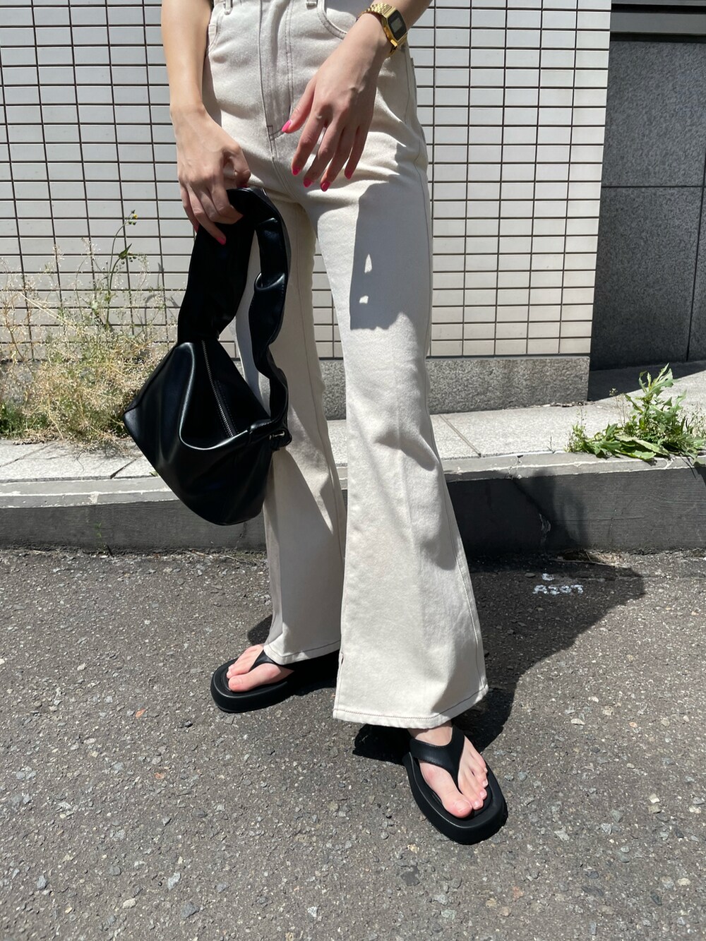 ホワイト系のデニムパンツ、ブラック系のサンダル、ブラック系のトートバッグを着用したレディースの夏コーディネートの3枚目の写真