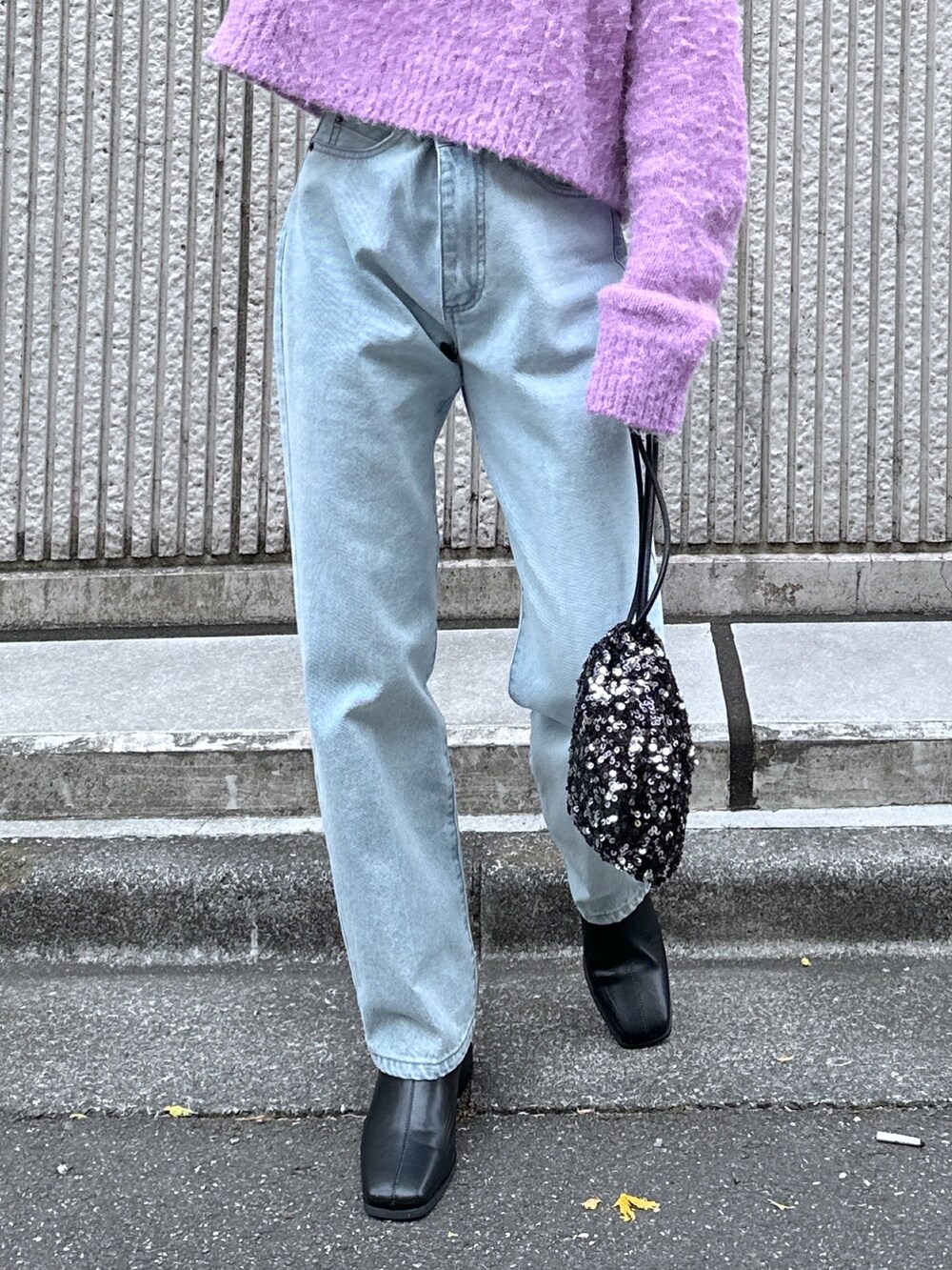 パープル系のニット/セーター、ブルー系のデニムパンツ、ブラック系のハンドバッグを着用したレディースの冬コーディネートの6枚目の写真
