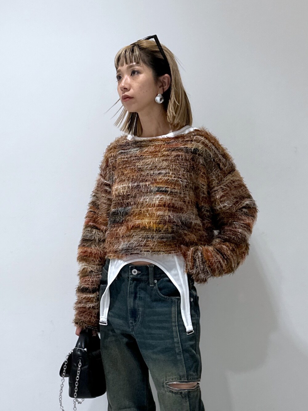 ブルー系のデニムパンツ、レッド系のニット/セーター、ブラック系のショルダーバッグを着用したレディースの秋コーディネートの4枚目の写真