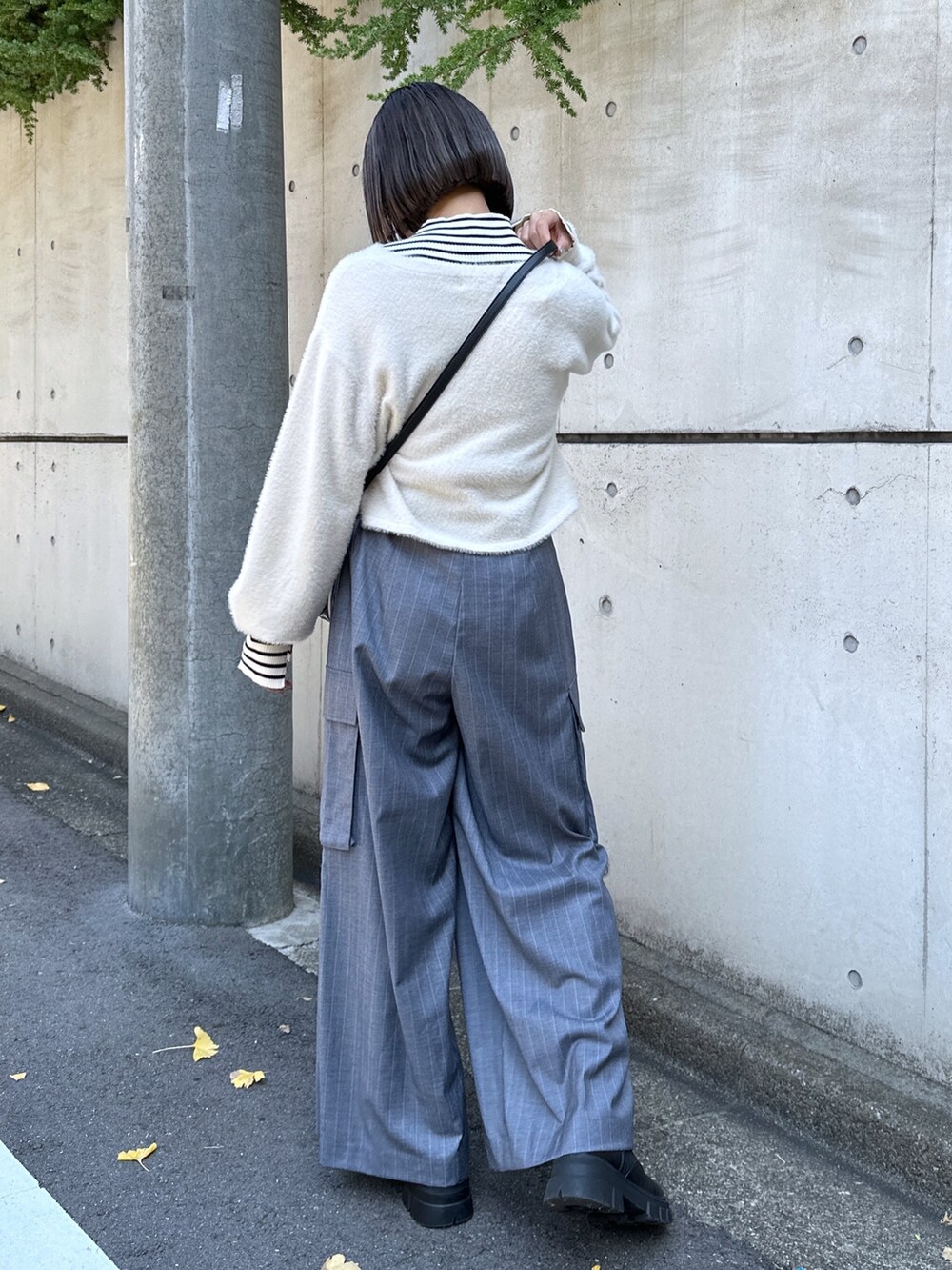 グレー系のスラックス、ブラック系のショルダーバッグ、ホワイト系のニット/セーターを着用したレディースの秋コーディネートの3枚目の写真