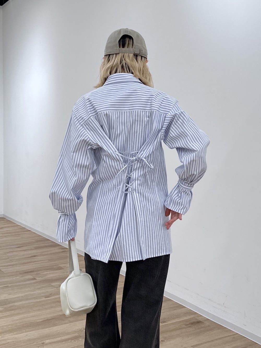 ブルー系のシャツ/ブラウス、ブラック系のデニムパンツ、ホワイト系のハンドバッグを着用したレディースの冬コーディネートの5枚目の写真