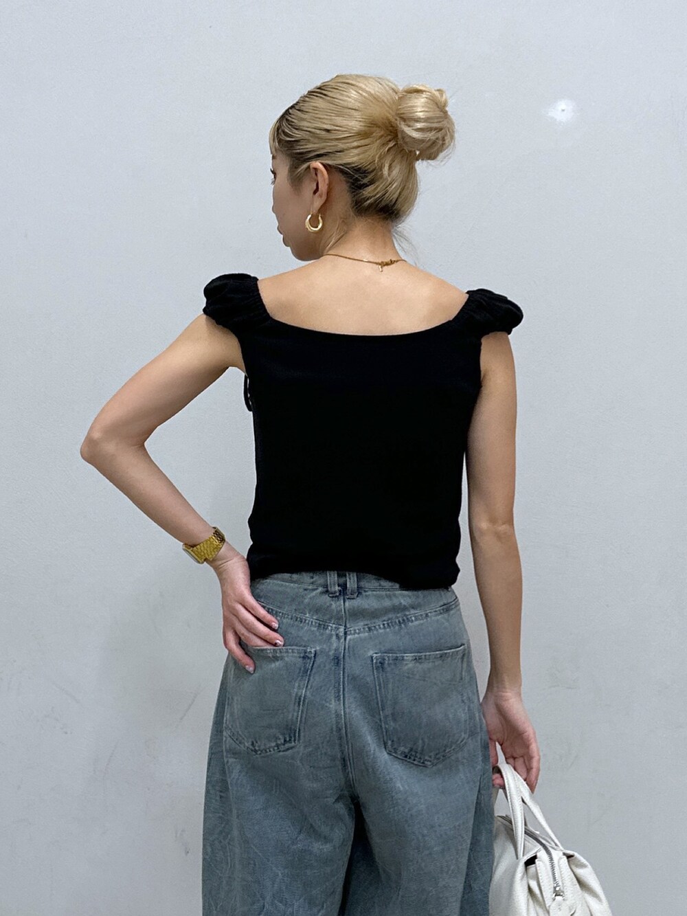 ブラック系のTシャツ/カットソー、ブルー系のデニムパンツ、ゴールド系のパンプスを着用したレディースの春コーディネートの5枚目の写真