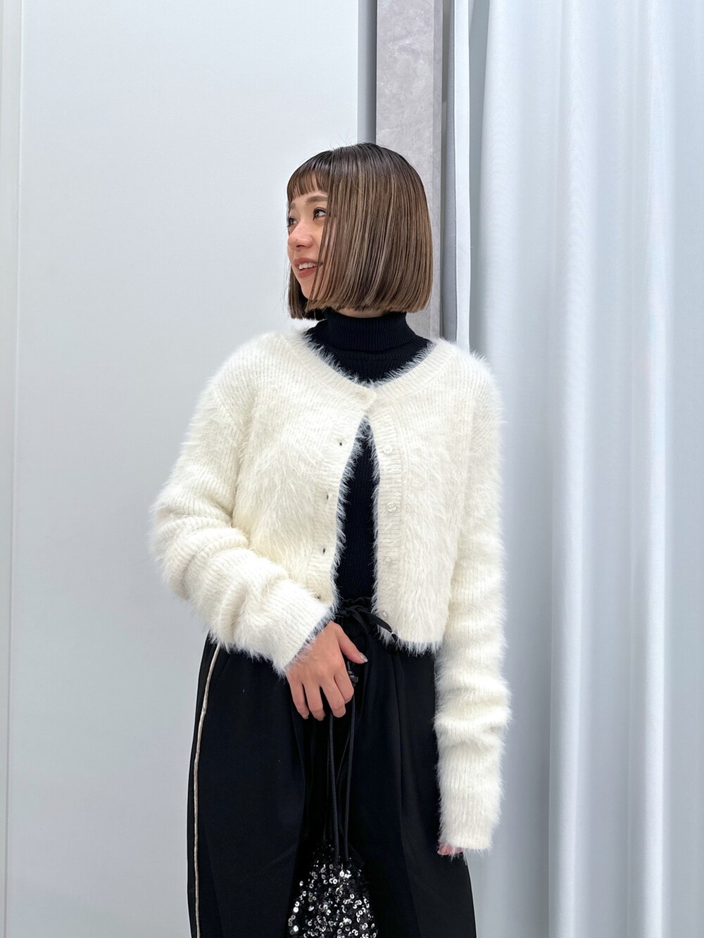 ブラック系のその他パンツ、ブラック系のハンドバッグ、ホワイト系のカーディガン/ボレロを着用したレディースの冬コーディネートの2枚目の写真