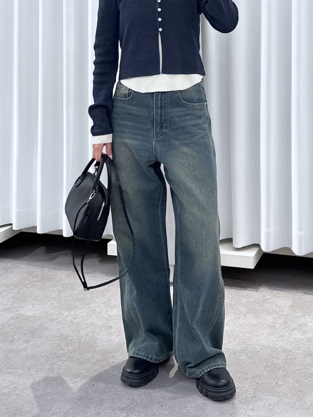 ブルー系のニット/セーター、ブルー系のデニムパンツ、ブラック系のハンドバッグを着用したレディースの春コーディネートの6枚目の写真