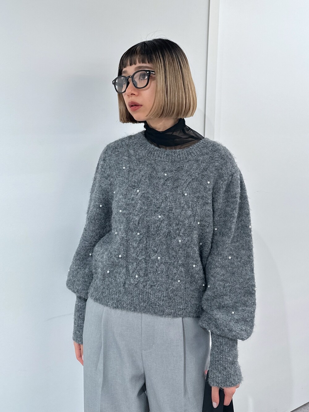 グレー系のスラックス、グレー系のニット/セーター、ブラック系のショルダーバッグを着用したレディースの冬コーディネートの4枚目の写真